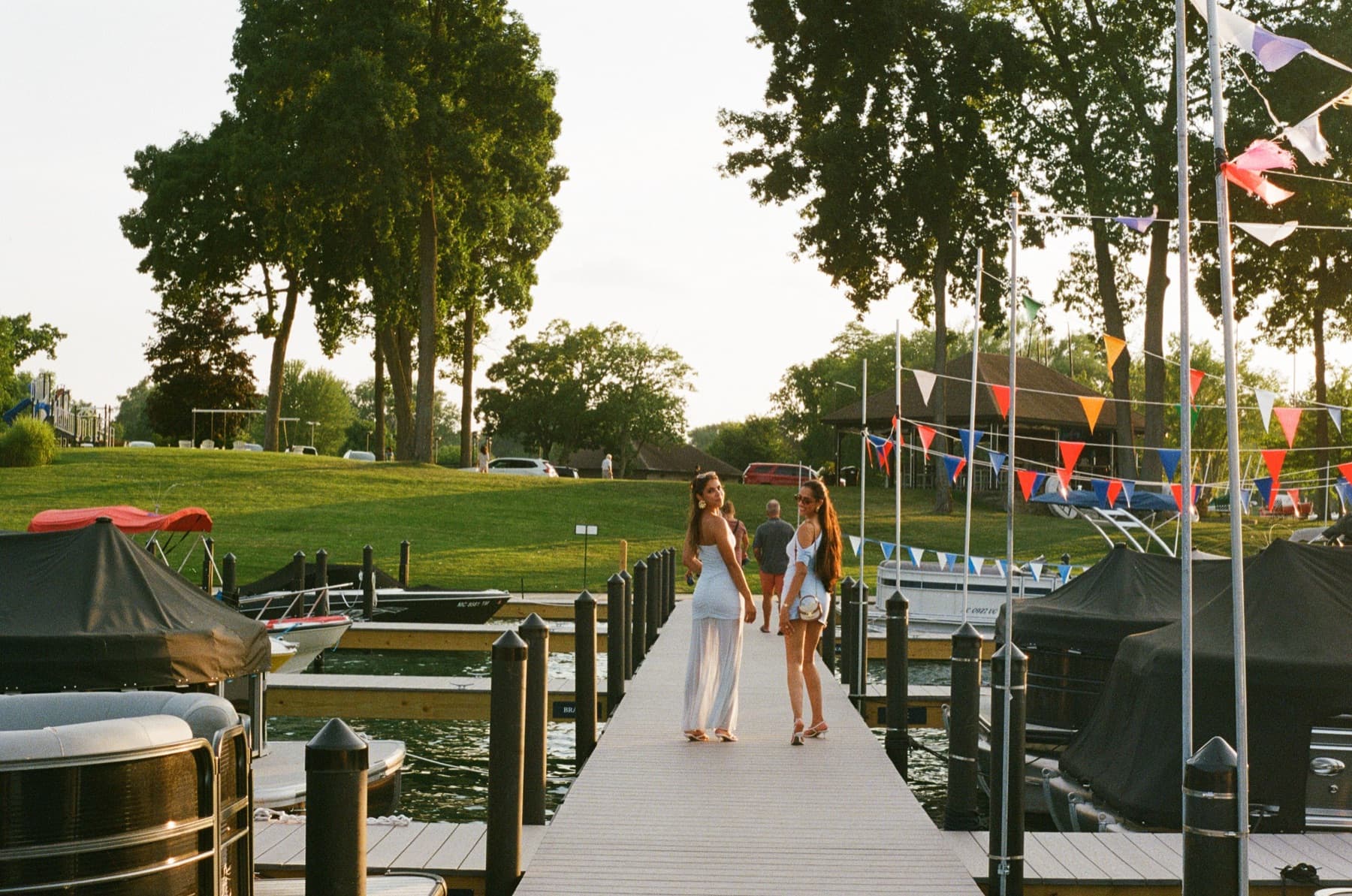Two friends in rented dresses on a summer marina dock